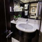 Httpswww Andyquinones Net modern bathroom with a dark wood vanity white oval sink and a vase of white orchids on the counter